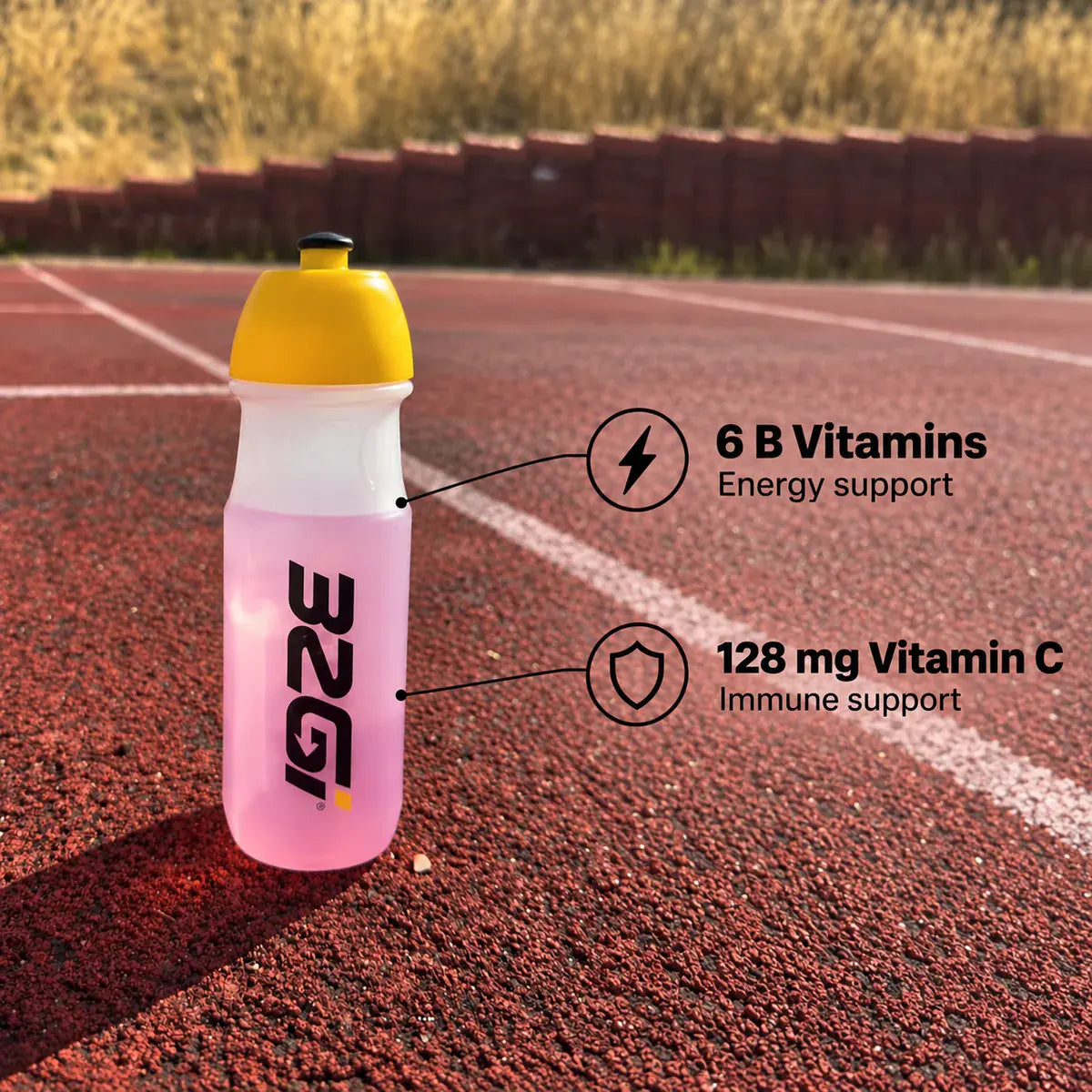A 32GI bottle of pink Hydrate on a running track, labelled six B vitamins for energy support and 128 mg vitamin C for immune support