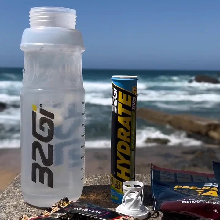A 32GI bottle and a tube of Hydrate on a wall above the sea, with other 32GI products beside them